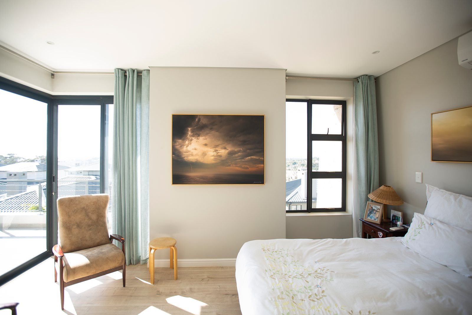 The same bedroom with a large framed storm seascape hung on the wall