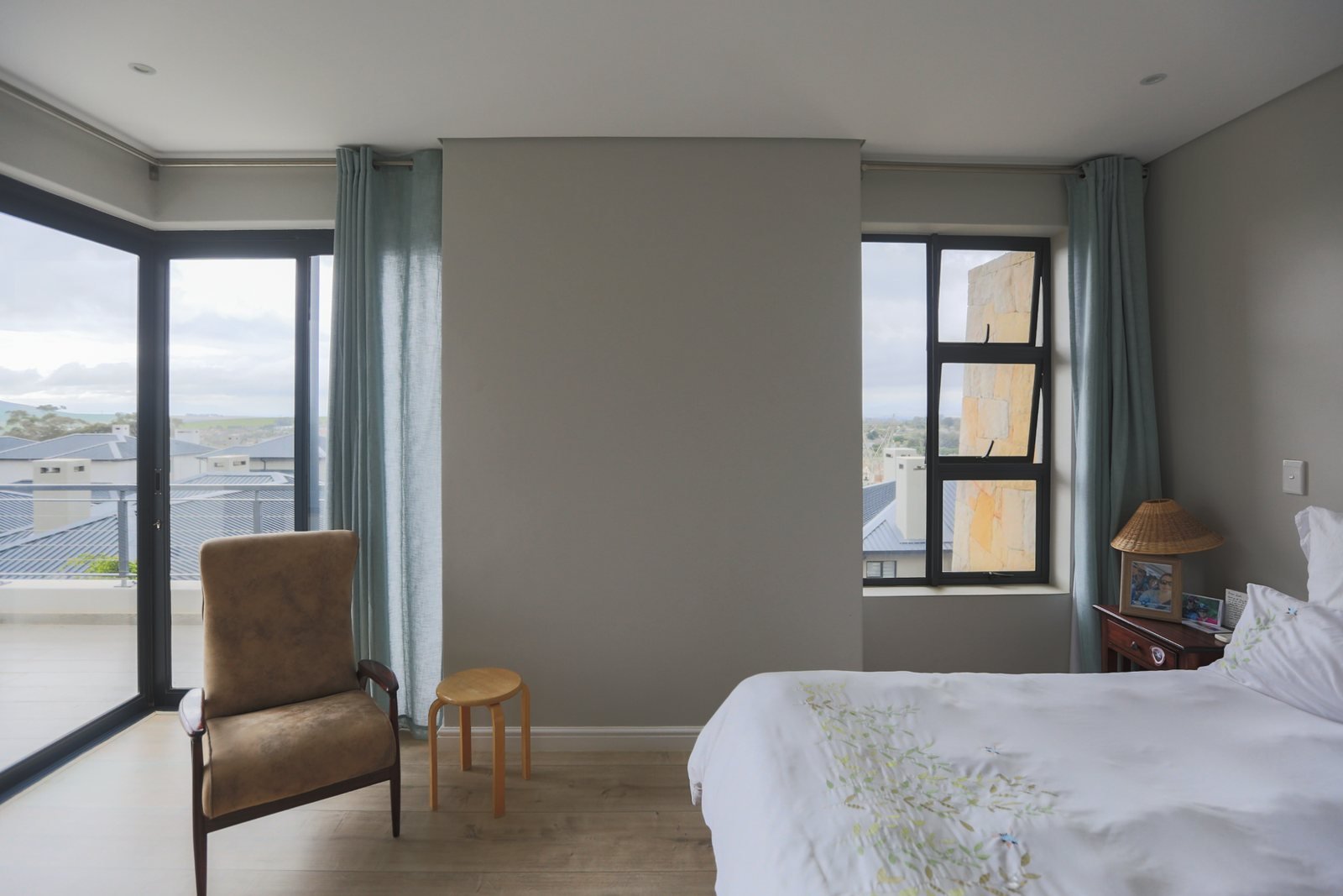 A bedroom with one bare grey wall between two windows, before any art was hung