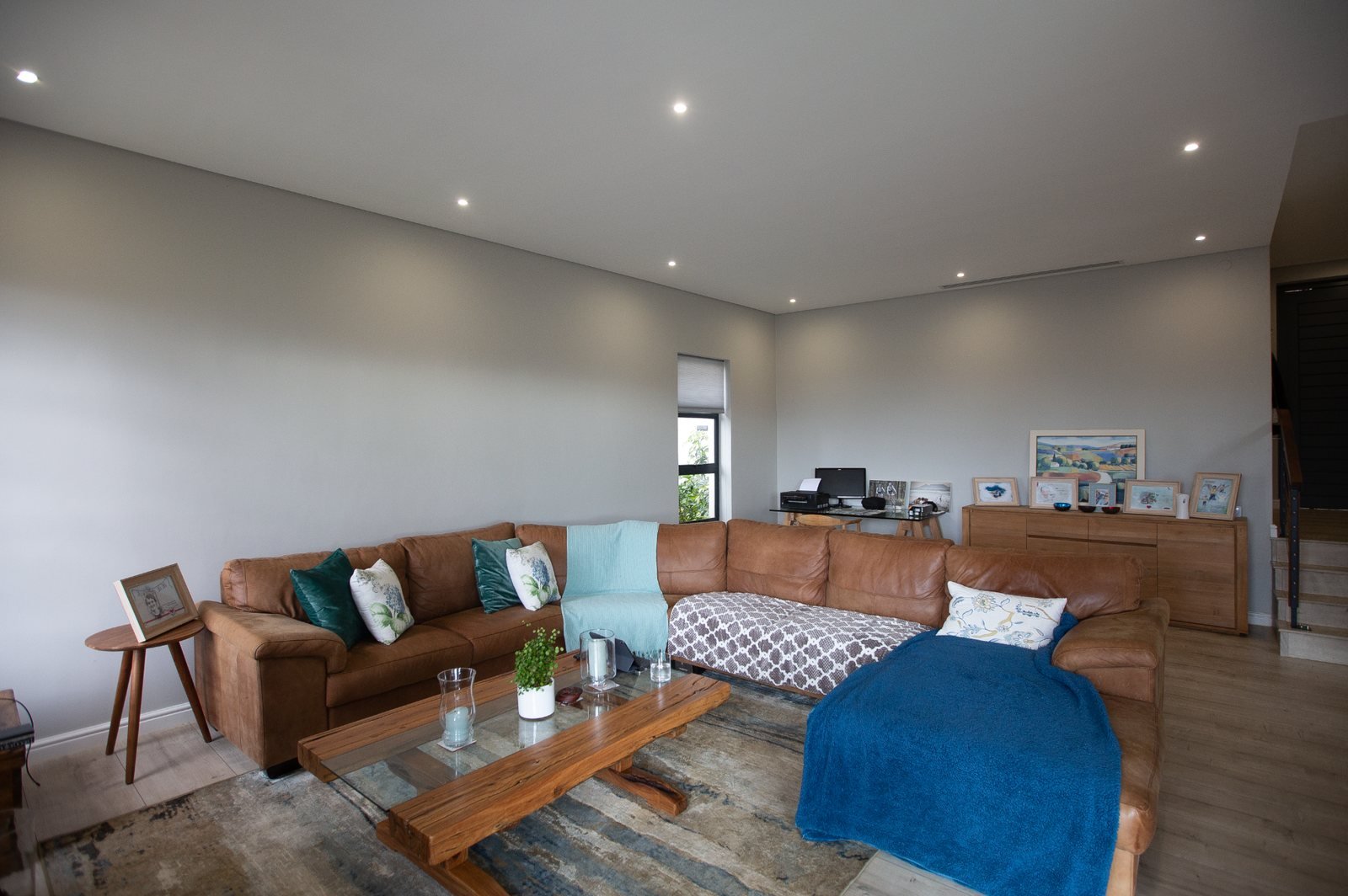 A lounge with bare walls and a picture leaning on the sideboard, before the art was hung