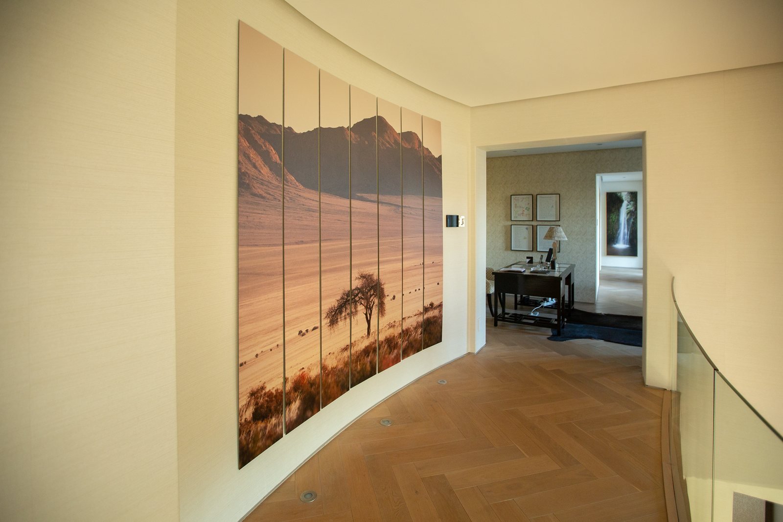 A very large landscape artwork on a curved wall along an upstairs passage