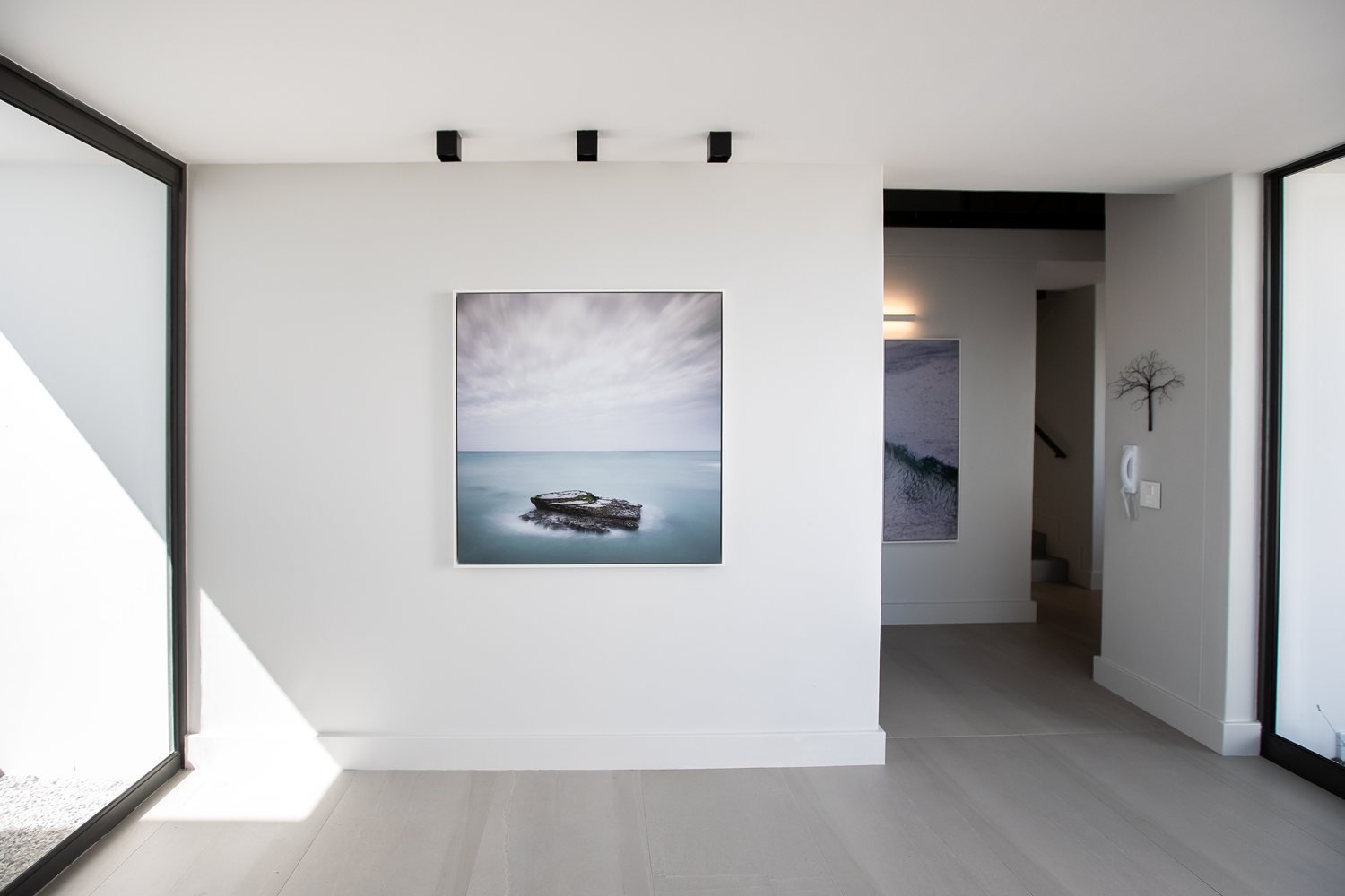 A large calm seascape artwork on a white wall in a modern entrance hall