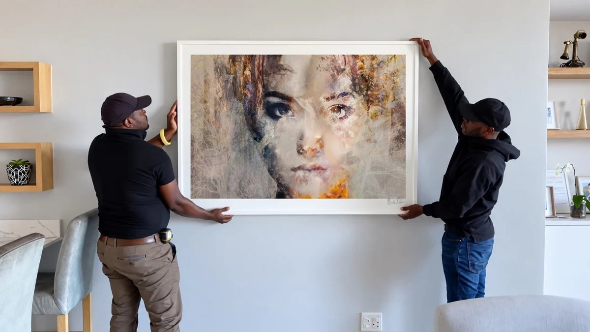Two members of the Osner Gallery team hanging a large framed print in a client's home