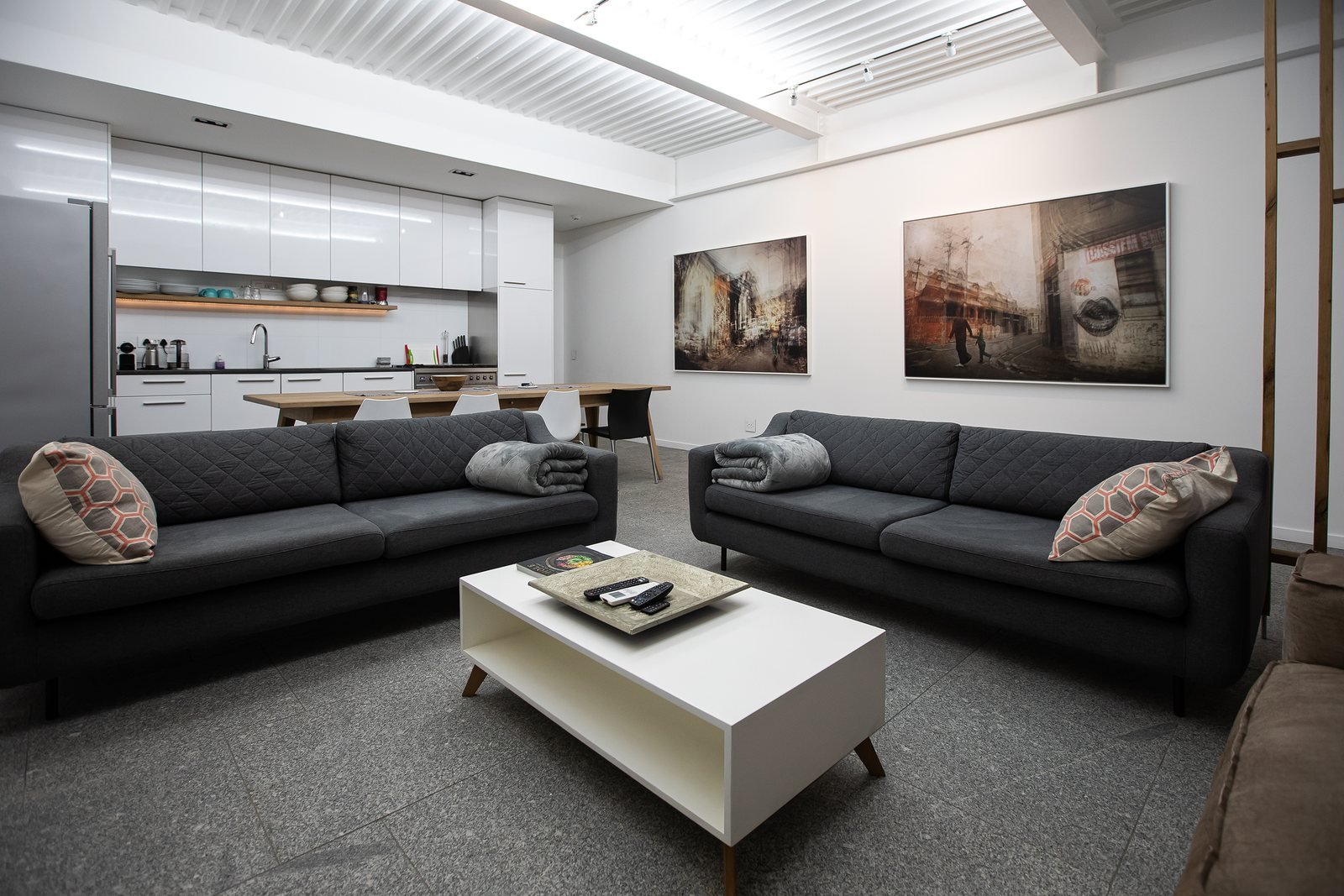 Two large artworks on the wall of an open plan living room and kitchen