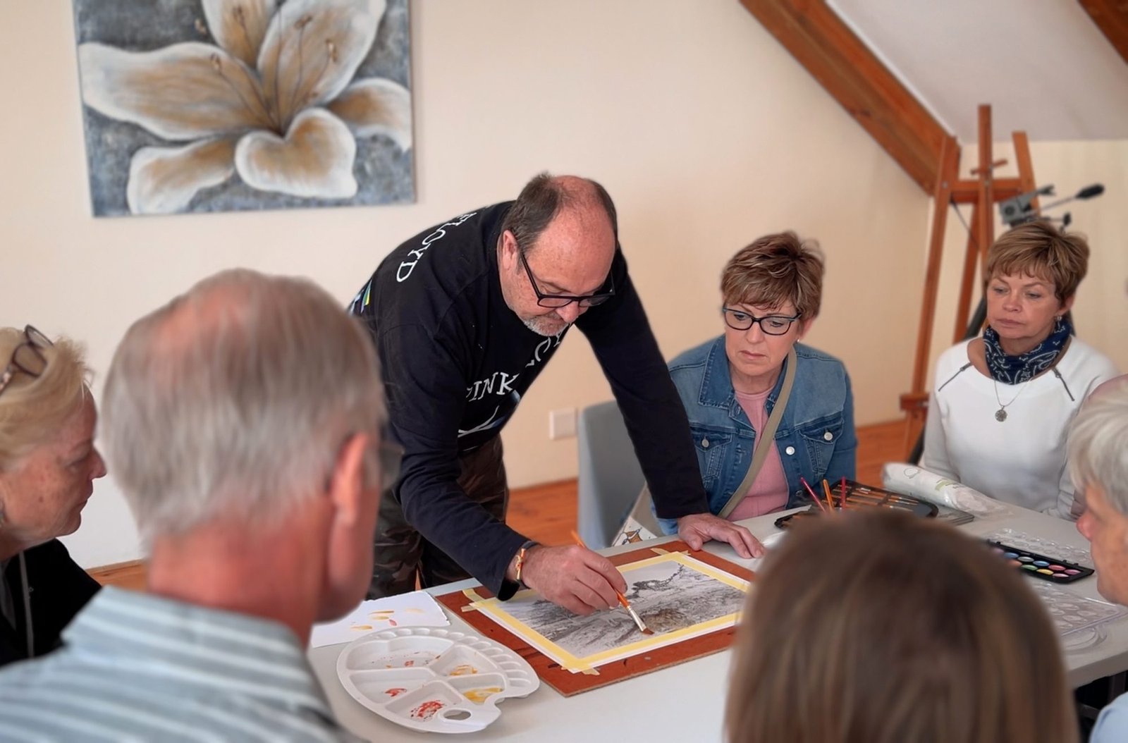 Martin Osner painting into a print at the studio table, students gathered round
